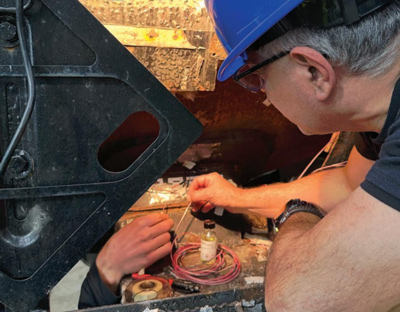 ENSCO engineer instrumenting a tank car for on-track testing at the TTC, installing sensors and wiring to capture real-time vehicle response and Wheel/Rail interaction data - TTC Operated by ENSCO - RT&S May 2026